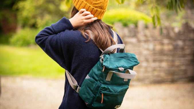 A woman wears a marine colour ROKA rucksack